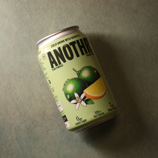 Green can of 'ANOTHR' drink with lemon and lime graphics on a gray background. Another kind of cold drink